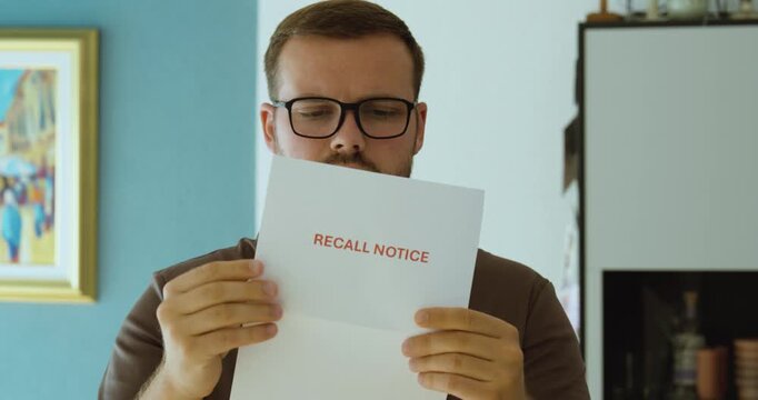 Man reading a recall notice document, representing product recall, safety warning, defective goods and important customer notification.