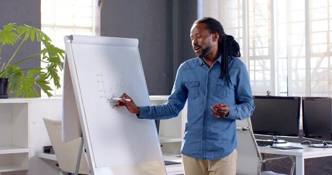 African American man presenting business graph on flip chart in modern office