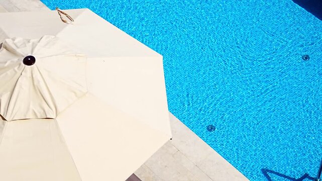 Luxury outdoor swimming pool with sun umbrellas viewed from above at a modern resort. Summer vacation, relaxation and premium hospitality lifestyle.