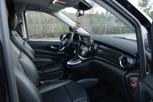 Luxurious interior of a black Mercedes-Benz V-Class featuring premium brown leather upholstery and a bright white headliner. Spacious executive cabin, high-end business shuttle comfort, elegant interi