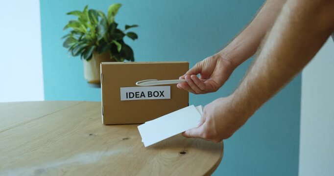 Man explaining how an idea box works, showing how employees can write and submit suggestions for workplace improvement.