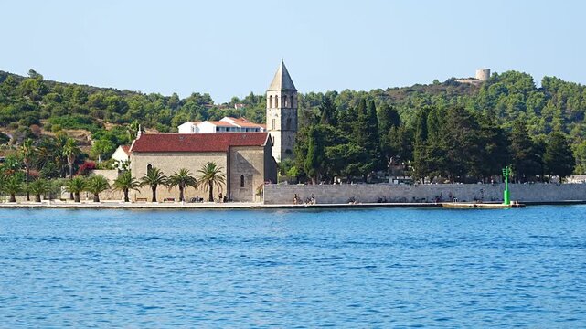View of the historic Franciscan Monastery surrounded by the Adriatic Sea, waterfront, palm trees and Mediterranean landscape on a sunny summer day.