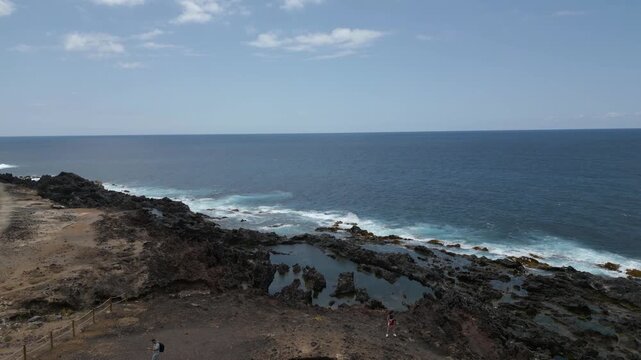 Visitors explore rocky El Rayo arch and natural pools by the Atlantic coastline