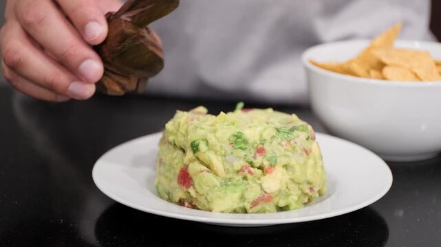 Crushed chiltepin pepper is sprinkled over fresh guacamole before it is enjoyed with crunchy tortilla chips