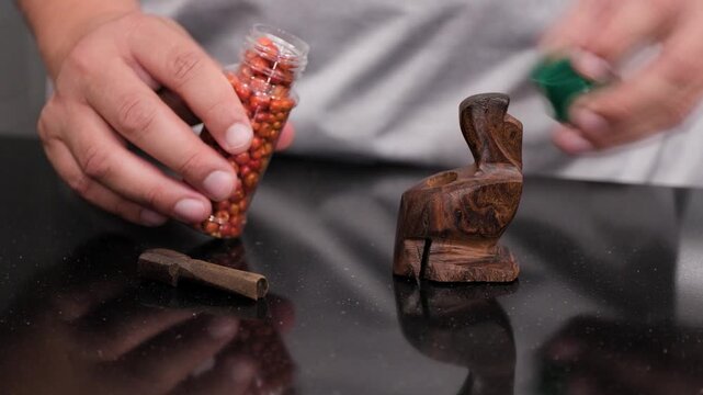 Dried chiltepin peppers are placed into a small mortar while preparing a spicy traditional Mexican seasoning