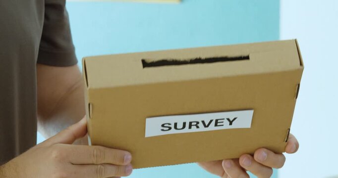 Close-up of a person holding a survey box, representing feedback collection, questionnaires, opinions and participation.
