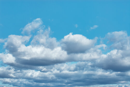 Wide view of a bright blue sky filled with layered white cumulus clouds, evoking calm, serenity and open space. Ideal for backgrounds, weather concepts, travel imagery and peaceful design projects.