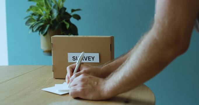Man completing a survey form and placing it into a survey box, representing feedback, voting, opinion and participation.