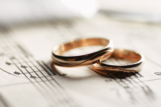 Two gold wedding rings rest on vintage sheet music, evoking romance, commitment and a musical connection for couples, engagements, ceremonies and anniversary celebrations.