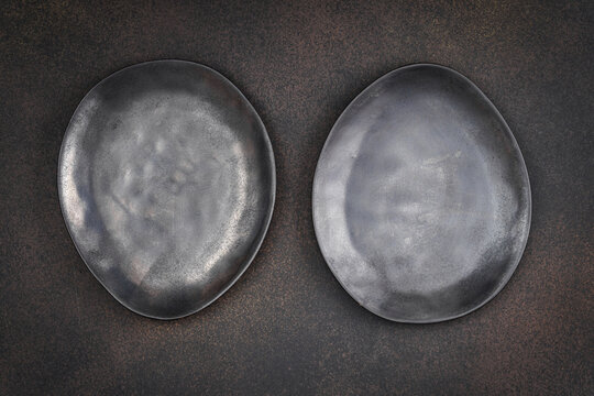 Two dark plates on textured background offer culinary setting