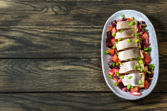 Herring pieces are arranged on bed of vibrant vinaigrette vegetables