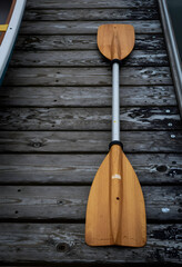Fototapeta premium Outdoor recreation and adventure travel, wooden kayak paddle resting on a weathered wooden dock by the water for summer vacation and leisure activity