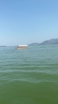 Tourist excursion boat cruises across the green waters of a scenic lake