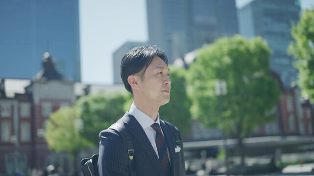 Japanese businessman standing in front of Tokyo Station on a sunny morning