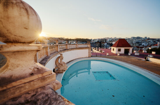 A park terrace with an empty pool and a cityscape view at sunset.