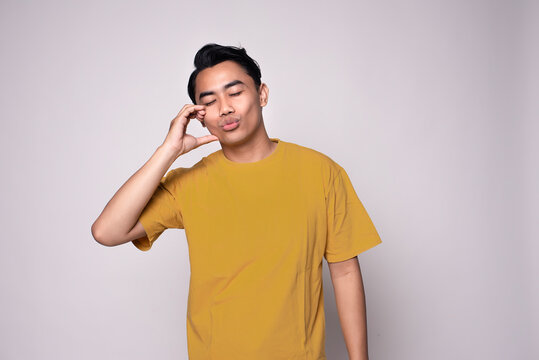 Young Asian Man doing heart gesture or sign expressing romantic feelings, isolated on white background