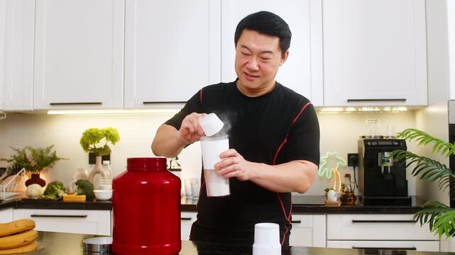 Man adds whey protein powder into small shaker bottle in home kitchen before training. Sports supplement drink supports muscle recovery energy balance healthy diet routine for gym fitness lifestyle.