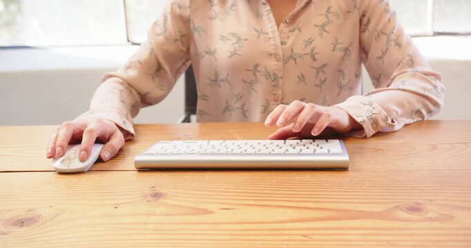 Hands typing on wireless keyboard at office desk, focusing on work