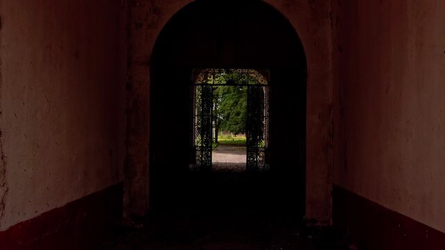Stone archway opening onto a garden path surrounded by tropical trees and plants. Lush greenery and landscaped borders create a peaceful outdoor setting in Mexico.