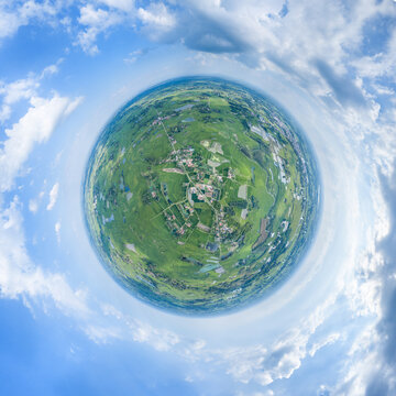 A tiny planet styled panoramic view showing rural fields, settlements and blue sky, depicting a natural landscape.