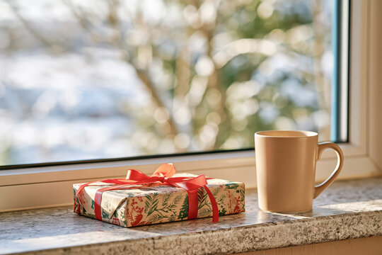 Cozy winter window view with hot drink and gift