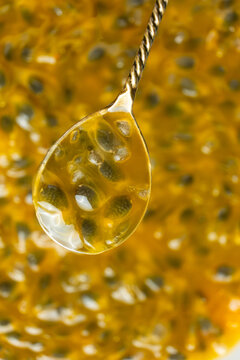 Close up of spoon holding fresh maracuja seeds and yellow pulp vertical view