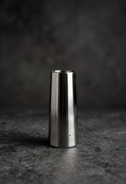 Mixology and cocktail preparation, stainless steel jigger for measuring alcohol and spirits in professional bar service on a dark textured background