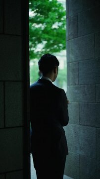 Silhouette of a Japanese businessman using a smartphone beside a column