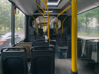Empty public bus interior with modern seats, yellow handrails, and large windows on city route. © stas_malyarevsky