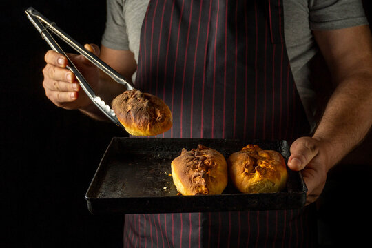 A chef, clad in a striped apron, skillfully holds a tray of golden pastries, ready to be savored. The warm kitchen emanates a delightful smell of freshly baked goods