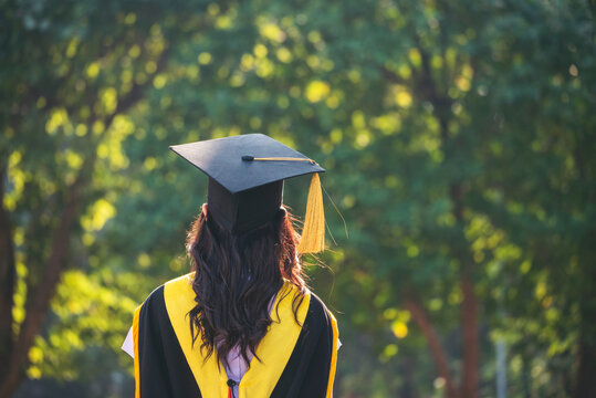 Portrait happy asian woman graduate student achievement academy wear black gown cap. Young woman backside graduated university. Back female college graduate bachelor degree standing in green park