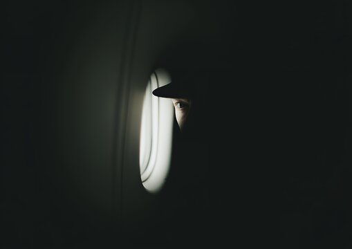 Mysterious eye peeking through small circular porthole in extreme dark shadow