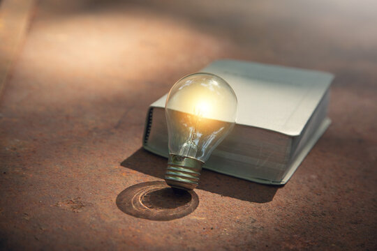 Light bulb and book on the old rusty background.