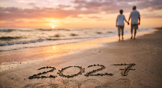 New Year inscription 2027 written in sand on beach at sunset with ocean waves and calm water suggesting peaceful start of future celebration.