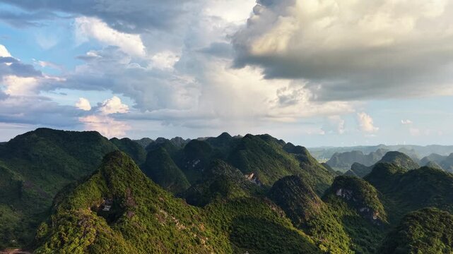 Landscape view: Rolling clouds over a vast karst mountain range with distant wind turbines