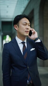 Businessman taking a call in a quiet colonnade of a Tokyo office building