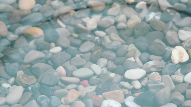 Falling Drops of Pure Water. Drops of water drip onto the surface of a small pond with clear water and a finely rocky bottom