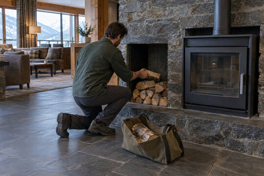 Mountain Lodge Worker Restocking Firewood Beside a Fireplace