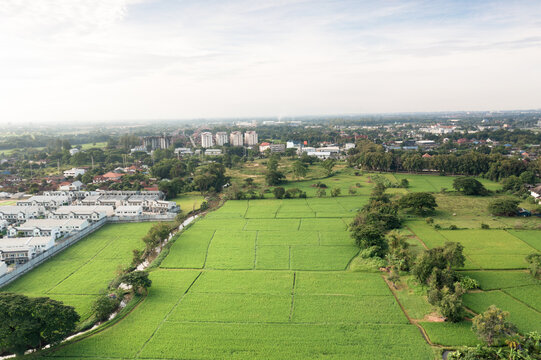 Aerial view of prime land in San Sai, Chiang Mai, Thailand, featuring green fields near residential communities, suitable for real estate investment, housing development, construction projects.