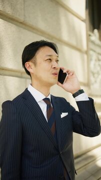 Smiling businessman having a friendly phone conversation in the city