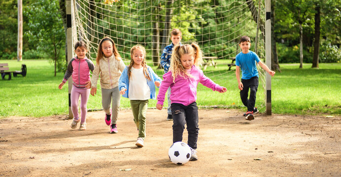 Group of young childs playing soccer ball outdoors in park