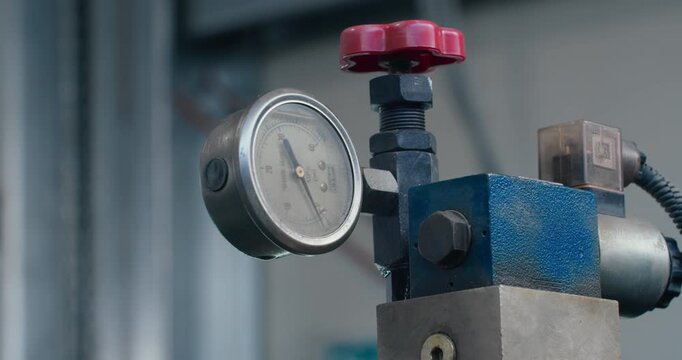 Analog pressure gauge on industrial equipment in factory workshop. Pressure monitoring and industrial instrumentation, close-up.