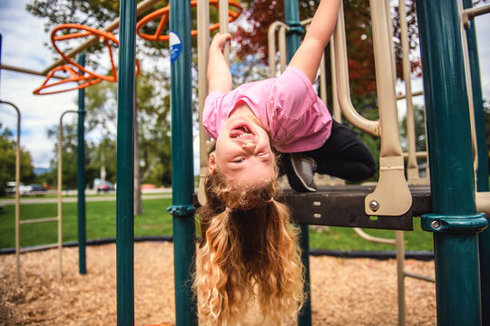 Little girl on on a playground having fun upside down