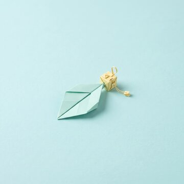 Elegant origami leaf design with a golden gift box on a soft blue background