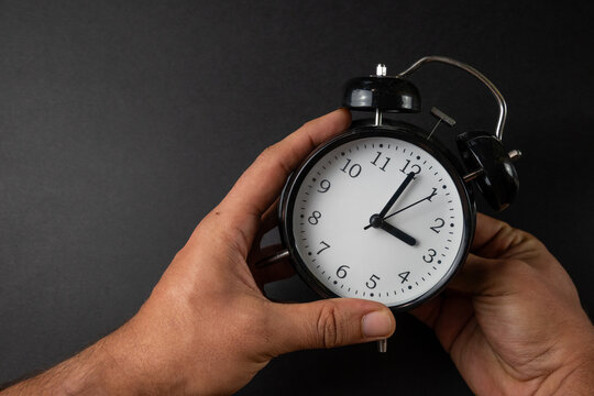 Hands adjusting alarm clock for time change