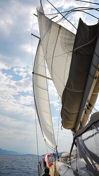 View from deck of sailing yacht with fully deployed sails cruising across Adriatic Sea under bright blue sky. Dynamic maritime travel scene representing freedom, adventure and nautical lifestyle
