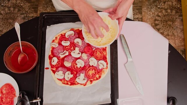 Woman preparing homemade pizza with mushrooms, tomatoes and salami. Close-up of home cooking before baking