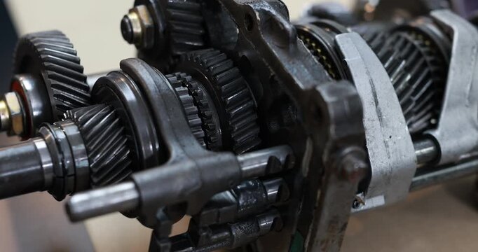 Close-up of metal gears and shafts inside a mechanical gearbox, industrial engineering parts with oil-worn texture.
