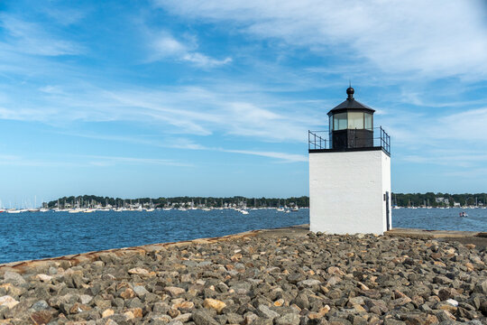 Lighthouse in Salem Harbor at Blue Hour, rocky breakwater with calm water and sailboats at blue dusk