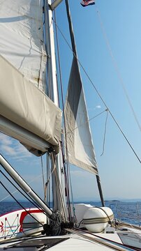 Jib sail unfurling on sailing yacht and filling with wind. Headsail opening during sailing at sea